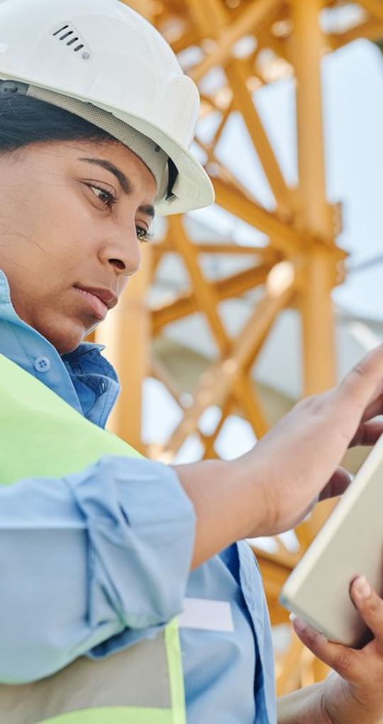 Tecnica con il casco consulta un tablet in cantiere.